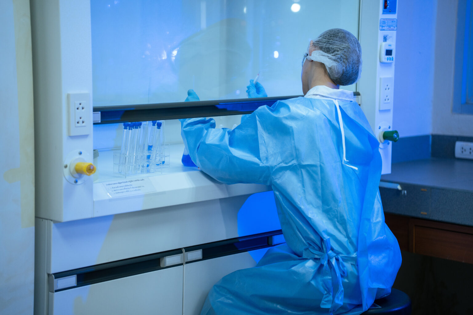 Compounding technician working at a sterile hood in a cleanroom